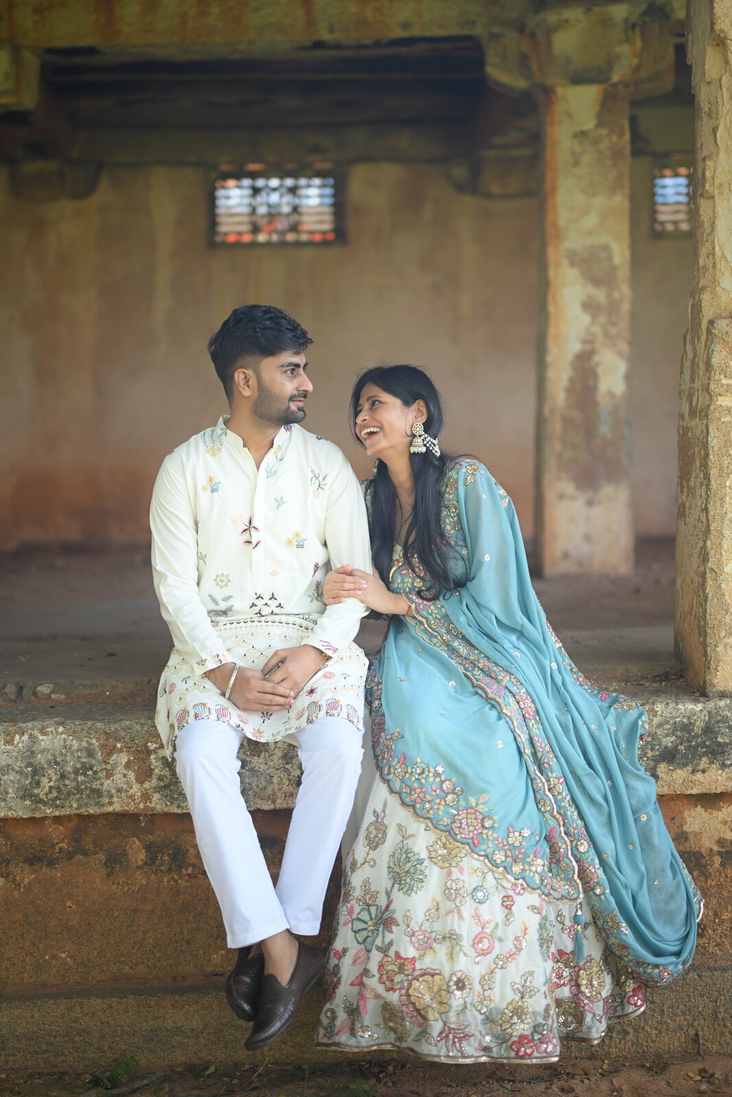 Priya and Ashish laughing together in elegant traditional attire