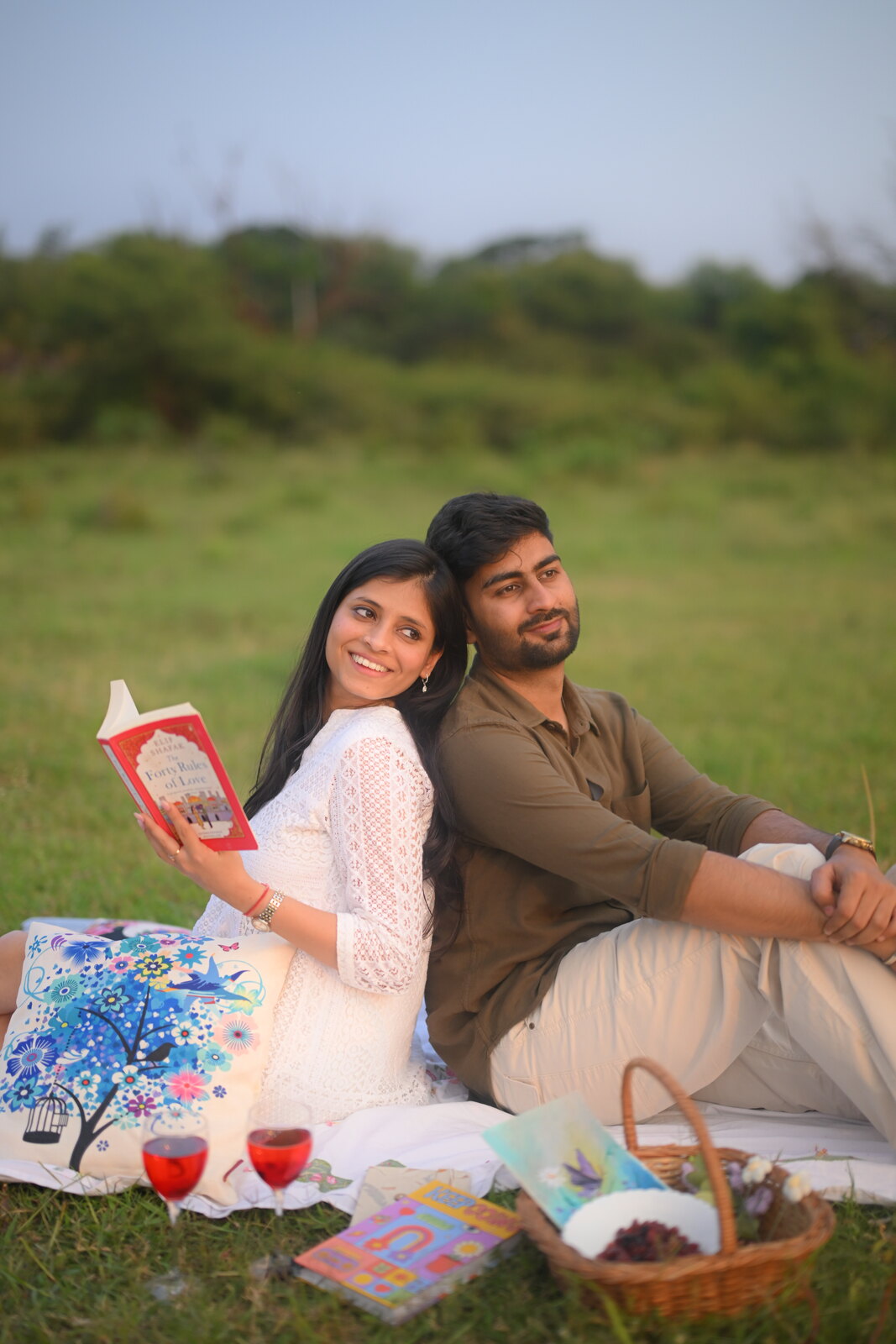 Priya and Ashish reading together during an outdoor picnic in a sunny meadow